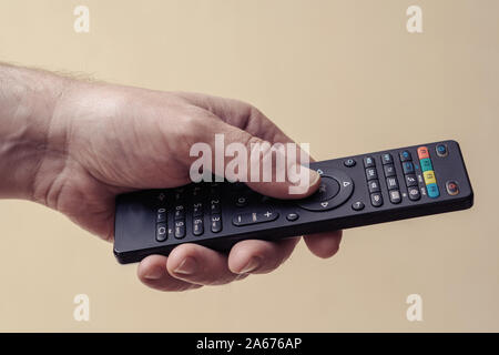 Männliche hand mit einer TV-Fernbedienung. Der Mann schaltet das Fernsehgerät Stockfoto
