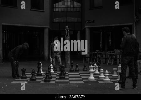 Ein schwarz-weiß Bild von Menschen spielen Giant Chess in der Straße (Amsterdam). Stockfoto