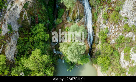 Ansicht von oben mit einem Wasserfall in den Bergen mit viel Vegetation umgeben. Blick von der Drohne Stockfoto