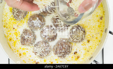 Fleischbällchen in saurer Sahne Sauce mit Parmesan auf einer Pfanne Nahaufnahme direkt von oben Stockfoto