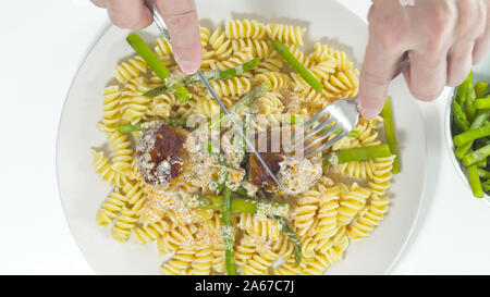 Pasta, Spargel, und Fleischbällchen in hausgemachte saure Sahne Sauce auf einer Platte in der Nähe bis auf weißem Hintergrund, Ansicht von oben Stockfoto