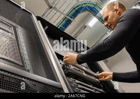 Männlicher IT-Techniker, der Server im Rechenzentrum installiert Stockfoto