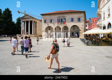 Touristen auf dem Marktplatz in Pula in Kroatien. Im Hintergrund der Augustus Tempel und das Rathaus. Stockfoto