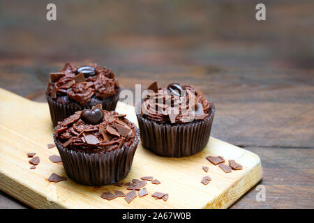 Chocolate Muffins mit Kakao Butter Creme auf einem Schneidebrett und einem dunklen Holztisch, Kopieren, ausgewählte konzentrieren, enge Tiefenschärfe Stockfoto