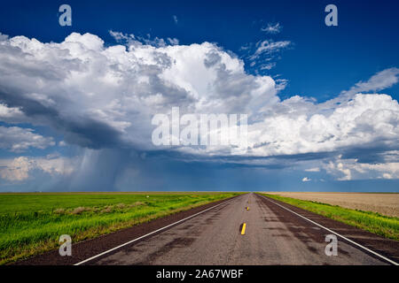 Eine gerade Straße führt in Richtung einer Cumulonimbus-Sturmwolke am Horizont in der Nähe von St. Francis, Kansas Stockfoto