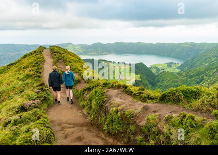 Ein junges Paar, das Hände beim Gehen in Richtung der Grota do Inferno Aussichtspunkt an Sete Cidades auf Sao Miguel, Azoren. Stockfoto