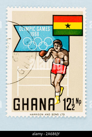 Nahaufnahme von Ghana Briefmarke feiert die Olympischen Spiele in Mexiko 1968. Stempel mit Ghana Flagge und Boxer, auf blauem Hintergrund mit kopieren. Stockfoto