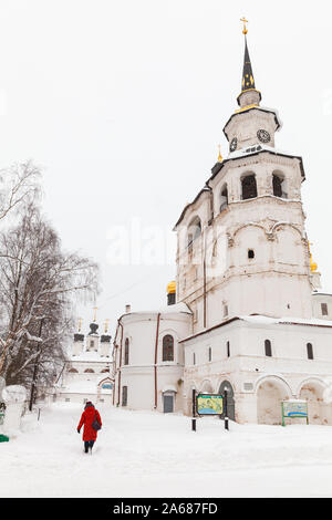 Weliki Ustjug, Russland - Februar 5, 2019: Frau in Rot Spaziergänge in der Nähe der Kathedrale, eine Orthodoxe Kirche in Weliki Ustjug, das älteste Gebäude in Th Stockfoto