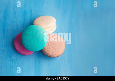 Süß und hell bunte Macarons auf blauem Hintergrund. Leckere französische Spezialitäten. Stockfoto