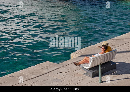 Ein Paar mittleren Alters, vermutlich verheiratet, allein in Gedanken entspannen, auf einer Bank an der adriatischen Küste in der kroatischen Insel Korcula. Stockfoto