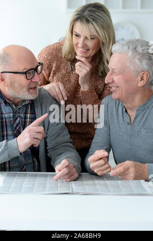 Ältere Leute am Tisch sitzen und Zeitung lesen Stockfoto