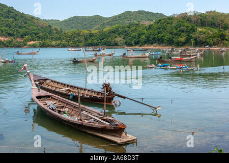 Viele tethered lange Fischerboote mit langen Propeller in der Bucht steht. Am Ufer Hügel mit grünen Bäumen bewachsen. Stockfoto