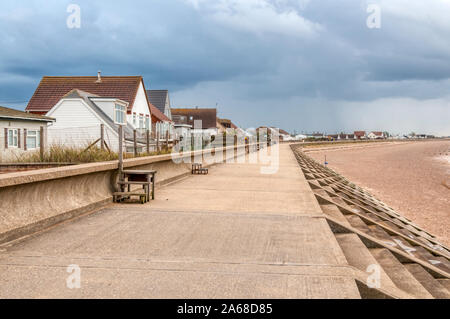 Schützende Sea Wall Überschwemmungen vor Seaside Bungalows mit Blick auf das Waschen bei Heacham in West Norfolk zu vermeiden. Mit storm Wolken. Stockfoto