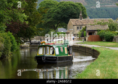 15-04 (schmale Boot) segeln am malerischen ländlichen Leeds Liverpool Canal, 1 Mann auf Stern (Lock & Tore darüber hinaus) - North Yorkshire, England, UK. Stockfoto