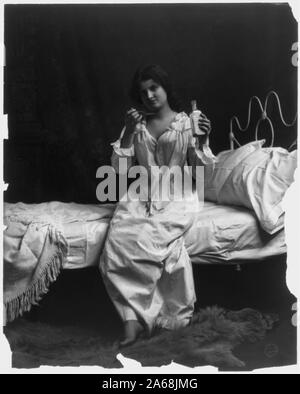 Frau auf dem Bett sitzt und die Löffel Medizin Stockfoto