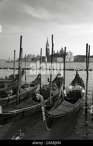 Chiesa di San Giorgio Maggiore, Venedig, Italien, über das Becken von San Marco: eine Linie der angelegten Gondeln im Vordergrund. Schwarz und Weiss Stockfoto