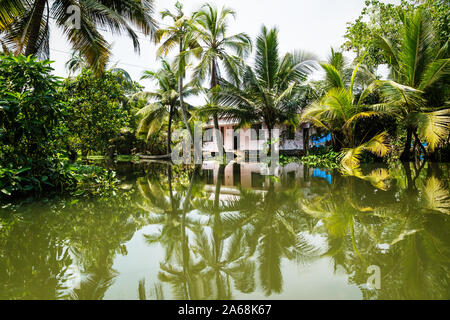 Haus in die Kerala Backwaters im üppigen Dschungel entlang des Kanals mit hellen Reflexionen, Alappuzha - New Delhi, Indien Stockfoto