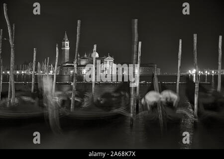 Chiesa di San Giorgio Maggiore, Venedig, Italien über das Becken des Hl. Markus im Morgengrauen: eine Linie der angelegten Gondeln im Vordergrund. Schwarze und weiße Versi Stockfoto