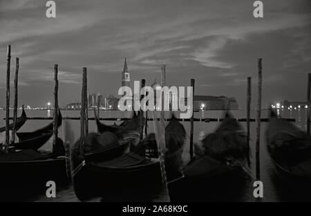 Chiesa di San Giorgio Maggiore, Venedig, Italien, über das Becken des Hl. Markus im Morgengrauen: eine Linie der angelegten Gondeln im Vordergrund. Schwarze und weiße Vers Stockfoto