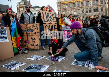 Ein Mann und ein kleines Mädchen Kerzen rund um das Plakat der Opfer in Chile Demonstrationen. Nach den Demonstrationen in Chile zu Forderungen nach Verbesserungen im Bildungs- oder Gesundheitswesen eskaliert, und die Löhne und verbreitete sich im ganzen Land, durch Frustration unter den Viele Chilenen, die fühlen, dass sie nicht in wirtschaftlichen Fortschritt des Landes geteilt haben. Hundert von chilenen am Dam Platz versammelt, in der Mitte von Amsterdam ihre Unterstützung mit den Menschen in Chile zu zeigen, und es möglich zu machen, damit die Menschen wissen, was in ihrem Land geschieht. Stockfoto