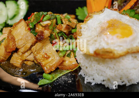 Nahaufnahme der Thailändischen würzigen Basilikum mit knusprigen Bauchspeck, Yardlong Bean und roter Chili servieren mit gestreamten Reis und Spiegelei. Stockfoto