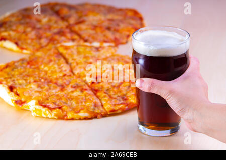 Nahaufnahme einer Person ein rotes Bier mit Pizza halten Stockfoto
