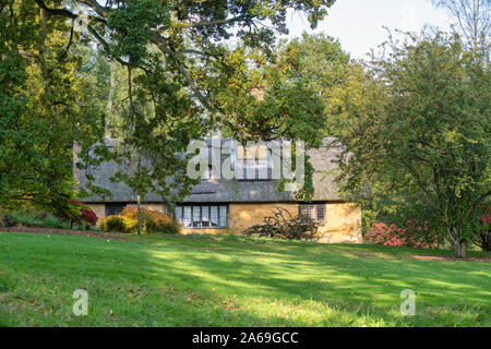 Reetdachhaus und Bäume im Herbst bei Batsford Arboretum, Cotswolds, Moreton-in-Marsh, Gloucestershire, England Stockfoto