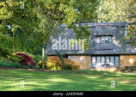 Reetdachhaus und Bäume im Herbst bei Batsford Arboretum, Cotswolds, Moreton-in-Marsh, Gloucestershire, England Stockfoto
