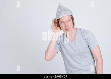 Junger Mann mit Alufolie hut Denken und Zuhören Stockfoto