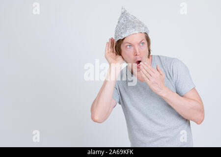 Junger Mann mit Alufolie hat hören und geschockt Stockfoto