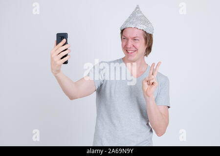 Glückliche junge Mann mit Alufolie hat unter selfie und Frieden Zeichen Stockfoto