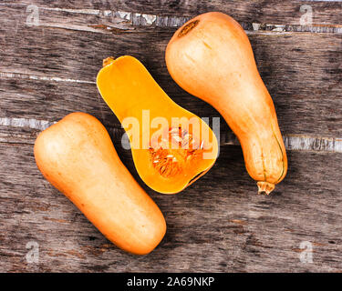 Kürbis auf einem schwarzen Holztisch. Süße Birne - 3 Orange Kürbis geprägt. Die Hälfte Kürbis geschnitten auf Mitte Stockfoto
