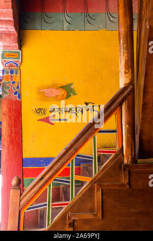 Ein gemaltes Schild mit Wegbeschreibungen und eine Hand auf dem Weg zur Toilette im buddhistischen Kloster Ganden auf Wangbur Mountain in Tibet. Stockfoto