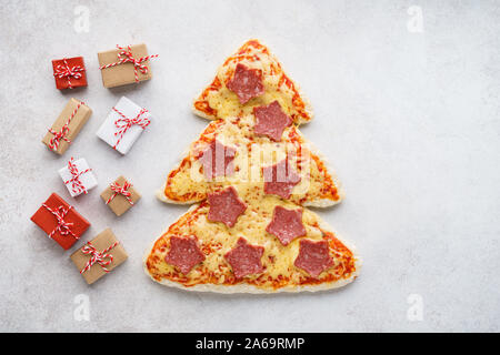 Weihnachten Pepperoni Pizza wie Xmas Tree und Geschenkboxen auf hellgrauem Hintergrund geprägt. Kopieren Sie Platz. Stockfoto