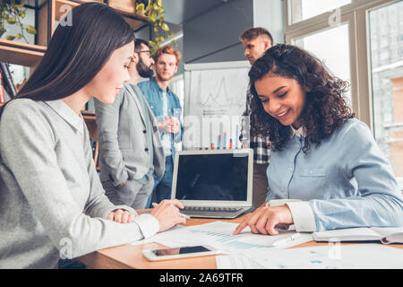 Startupers zusammen arbeiten im Büro Frauen am Tisch sitzen mit Blick auf die Dokumente mit Diagrammen heiter Stockfoto
