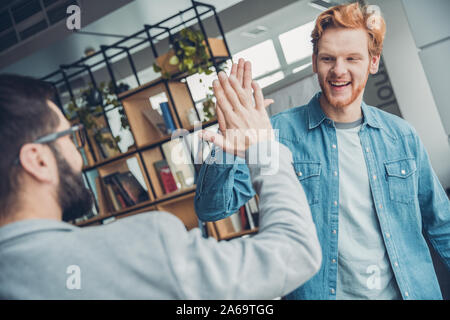 Männliche startupers zusammen arbeiten im Büro stehen hohe fünf lächelnde heiter Stockfoto