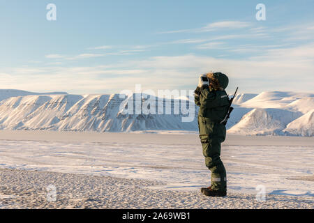Mann in arktische Landschaft. Stehende Person mit einem Gewehr und Fernglas, beobachten die arktische Landschaft auf Spitzbergen Stockfoto