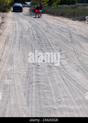 Sandigen weg. Spuren von verschiedenen Reifen und Spuren im Sand gedruckt. Ein Auto und zwei Touristen in der Ferne. Stockfoto