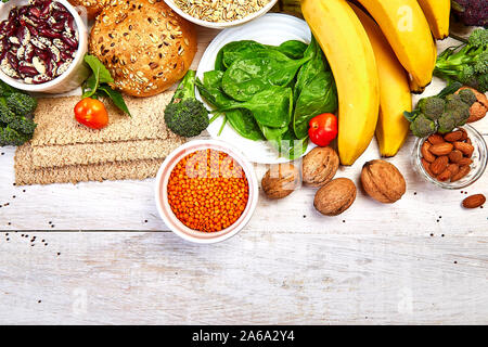 Einstellen der hohen Ballaststoffe Gesundheit Nahrung Produktkonzept mit Obst, Gemüse, Vollkornbrot, Hülsenfrüchten, Getreide, Nüsse und seedson weißen Holzmöbeln hinterg Stockfoto