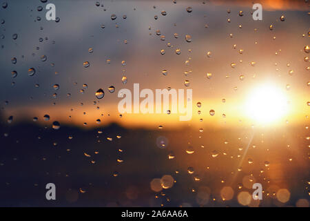 Regentropfen auf der Fensterscheibe bei Sonnenuntergang Stockfoto