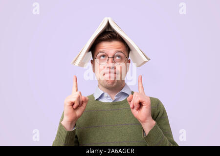Schöner Mann in Gläsern mit einem bookc am Kopf und nach oben Stockfoto