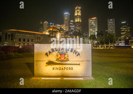 Die Singapur Parlament Gebäude mit einem Wolkenkratzer im Hintergrund bei Nacht Stockfoto