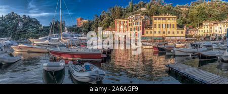 Panorama Blick auf den Hafen von Portofino, Italienische Riviera, Ligurien Italien mit angelegten Boote und Yachten vor bunten Gebäude am Wasser und üppige Gree Stockfoto