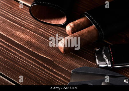 Stillleben mit kubanischen Zigarre in Ledertasche, Cutter und leichter auf alten Holzplatte Tisch mit Platz für Text. Stockfoto