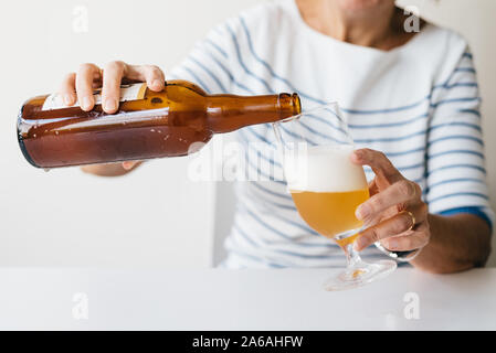 Frau gießen ein erfrischendes Bier im Glas. Stockfoto