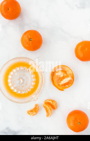 Clementinen und Citrus Glas Entsafter mit Saft auf weißem Hintergrund mit kopieren. Ansicht von oben. Stockfoto
