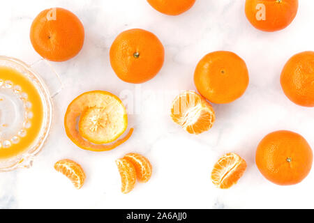 Clementinen, clementine Saft und Segmente in einer Zitruspresse auf weißem Hintergrund. Ansicht von oben. Stockfoto