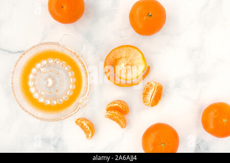 Entsafter Zitrusfrüchte Glas mit Saft und Clementinen auf weißem Hintergrund mit kopieren. Ansicht von oben. Stockfoto