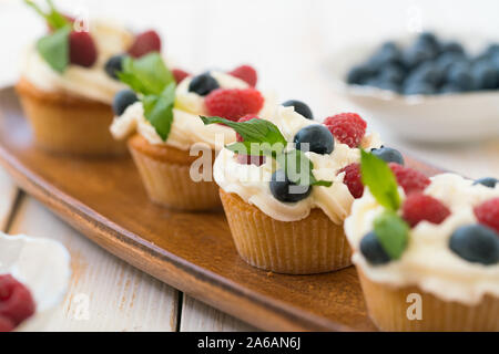 Leckere Muffins mit Beeren und frischer Minze auf hölzernen Tisch Stockfoto