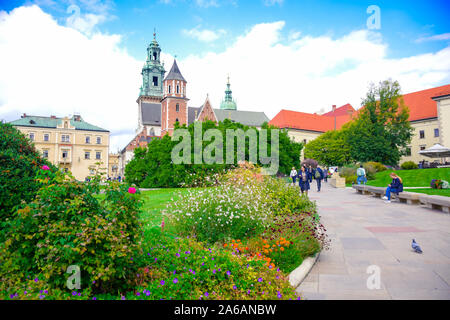 Touristen gehen durch einen Pfad mit der Blume courrtyard Garten mit Königsschloss Wawel und Kathedrale auf dem Wawel in Krakau, Hintergrund, zentrale Po Stockfoto